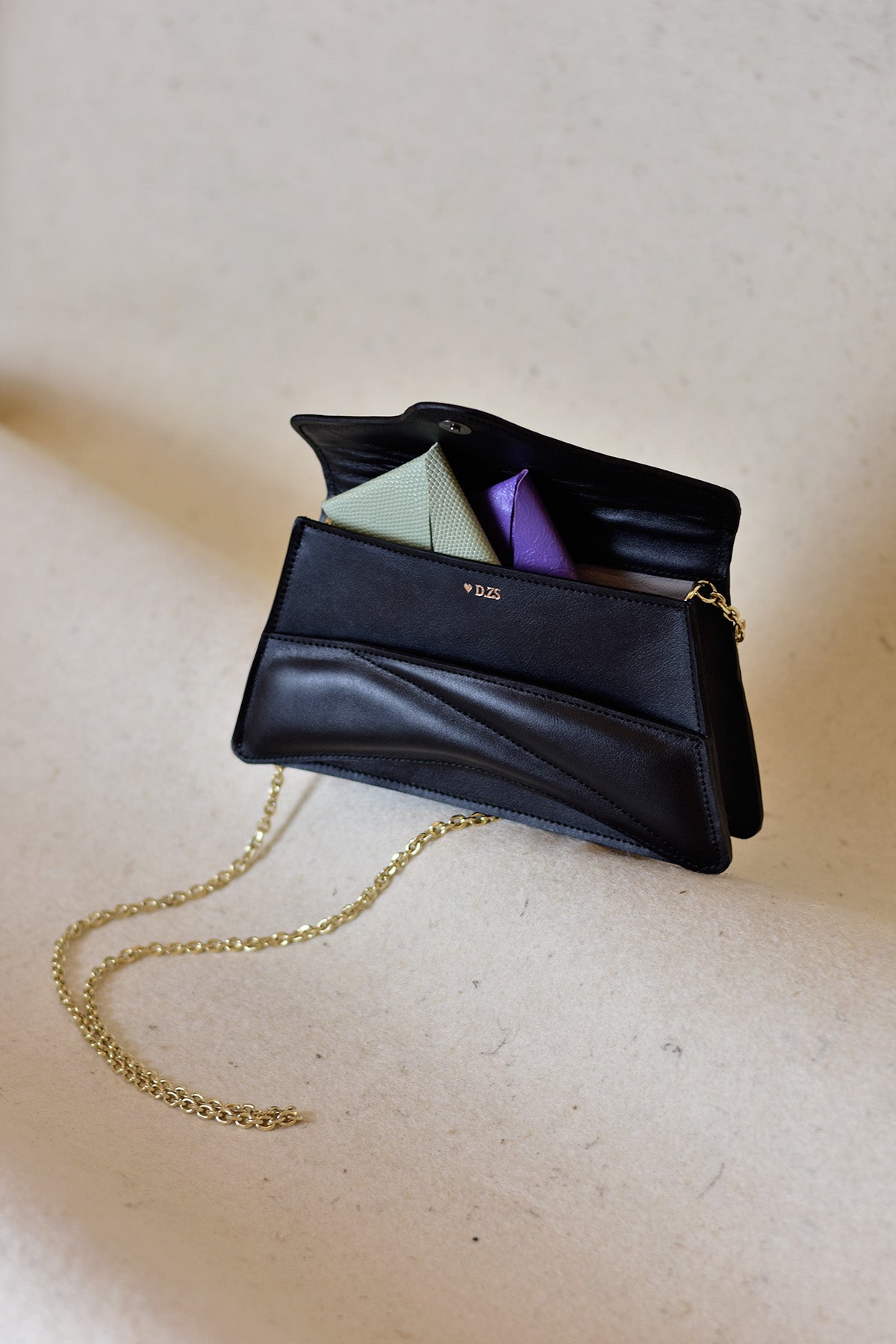 Handmade clutch bag handcrafted from genuine Italian leather, custom colors, black handbag, crossbody purse with unique wrist strap by Hungarian, Budapest based designer. Fekete, választható színű bőr designer borítéktáska, táska, válltáska magyar táskatervező márka.