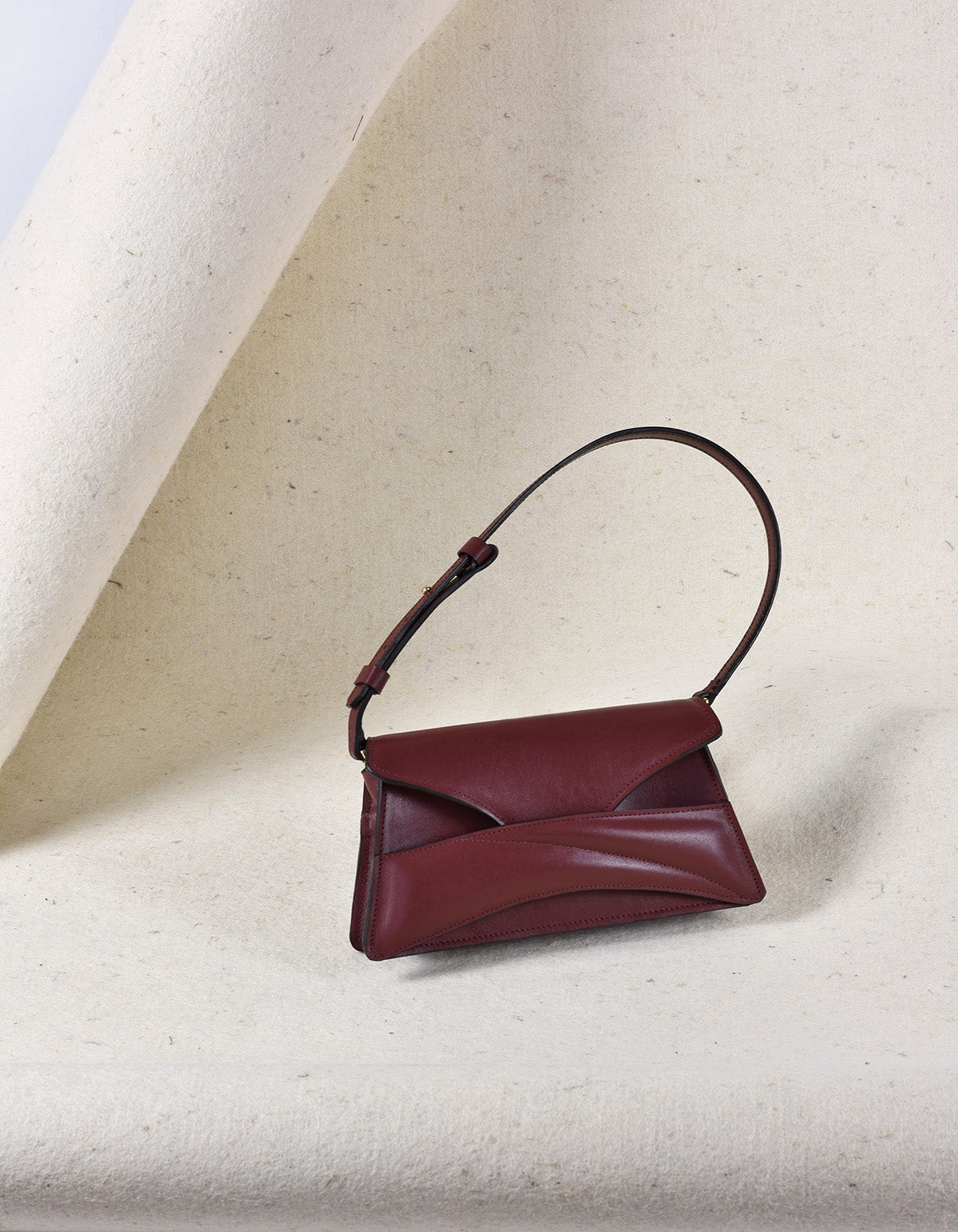 Handmade clutch bag handcrafted from genuine Italian leather, custom colors, dark red, burgundy, garnet, wine red handbag, crossbody purse with unique wrist strap by Hungarian, Budapest based designer. Bordó, piros választható színű bőr designer borítéktáska, táska, válltáska magyar táskatervező márka.