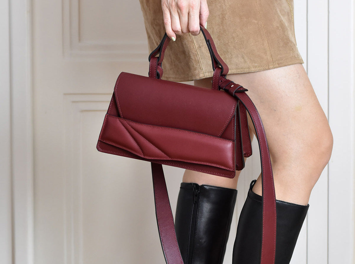 bordó piros magyar designer bőr táska camel őszi outfit. Dark red leather top handle shoulder bag with unique wrist strap by Budapest based designer