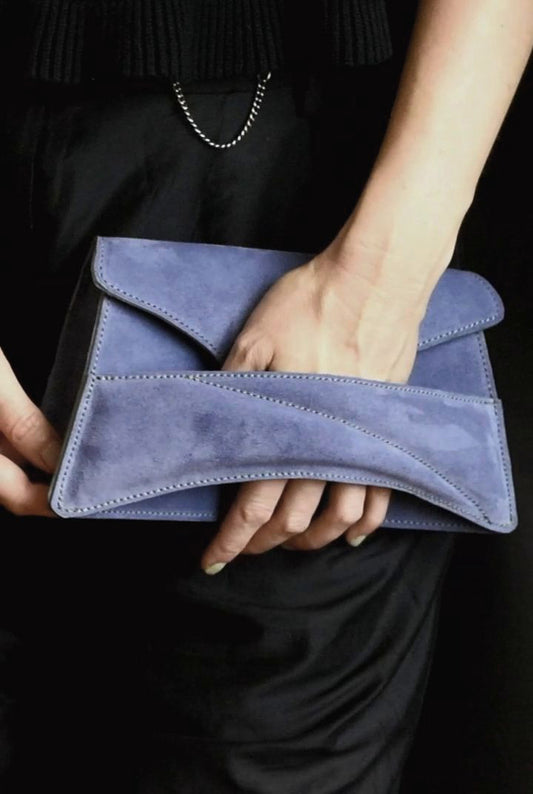 Lindasieto sculptural amethyst lilac suede leather Link Bag, designer crossbody handbag worn on the shoulder with black elegant minimal outfit. Magyar kortárs designer lila velúr bőr alkalmi clutch táska, kézben viselve, elegáns fekete neutrális öltözékkel