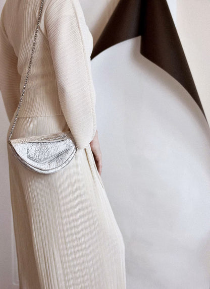 Sculptural clutch to shoulder bag handcrafted from plant-based,vegan material, elegant, silver handbag with unique wrist strap, by Budapest, EU based designer. Elegáns, magyar vegán designer borítéktáska, ezüst táska, magyar táska tervező márka.
