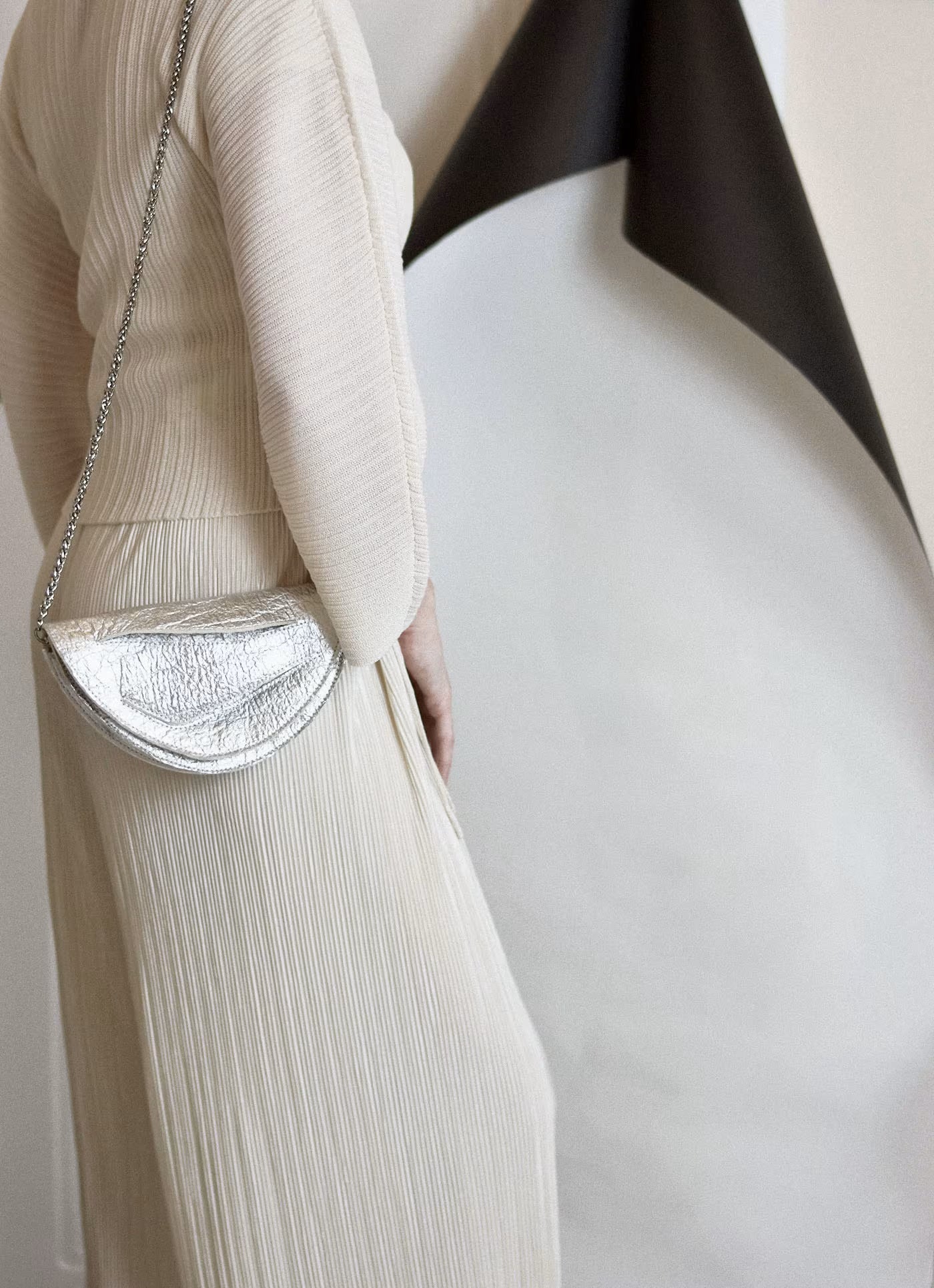 Sculptural clutch bag handcrafted from plant-based,vegan material, elegant, silver handbag with unique wrist strap, christmas gift edit by Budapest,EU based designer. Elegáns, magyar vegán designer borítéktáska, ezüst táska, karácsonyi ajándék, magyar táska tervező márka.