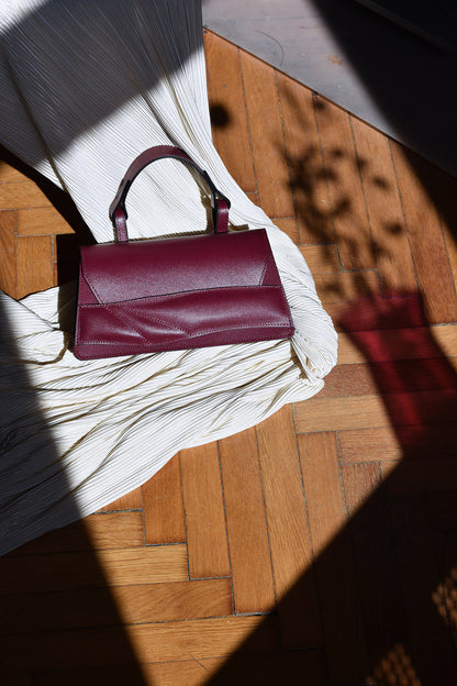 Handmade top handle bag crafted from genuine Italian leather, black cherry dark red handbag, crossbody purse with unique wrist strap by Hungarian, Budapest based designer. Egyedi cseresznye piros bőr designer táska,  magyar tervező márka.