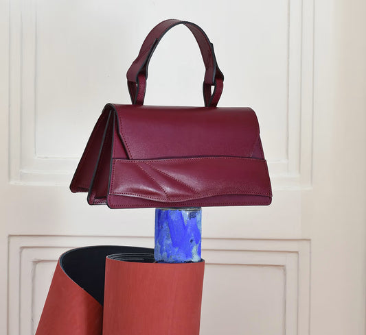 Handmade sculptural bag crafted from premium Italian nappa leather, black cherry red, oxblood coloured handbag, crossbody purse with unique wrist strap by Budapest based designer. Egyedi bordó bőr designer táska, kézzel festett élek, magyar tervezői márka.