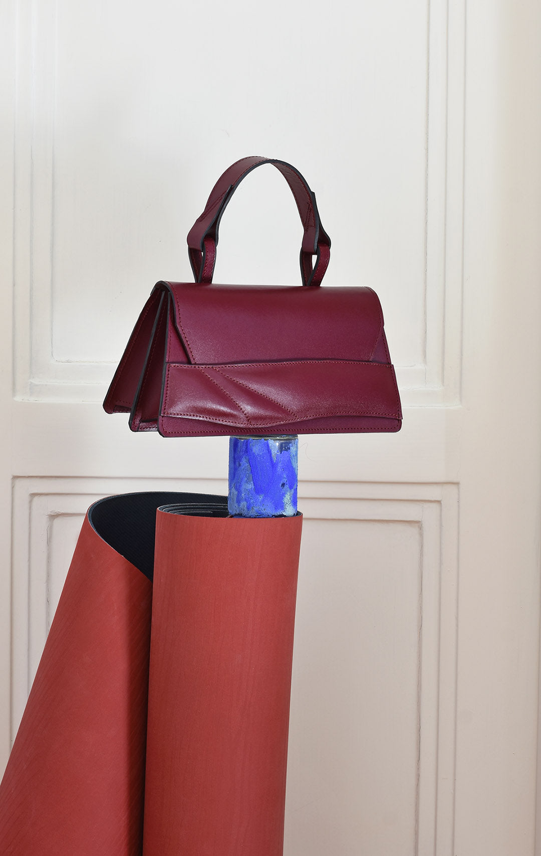 Handmade sculptural bag crafted from premium Italian nappa leather, black cherry red, burgundy handbag, crossbody purse with unique wrist strap by Budapest based designer. Egyedi burgundi bordó bőr designer táska, kézzel festett élek, magyar tervezői márka.