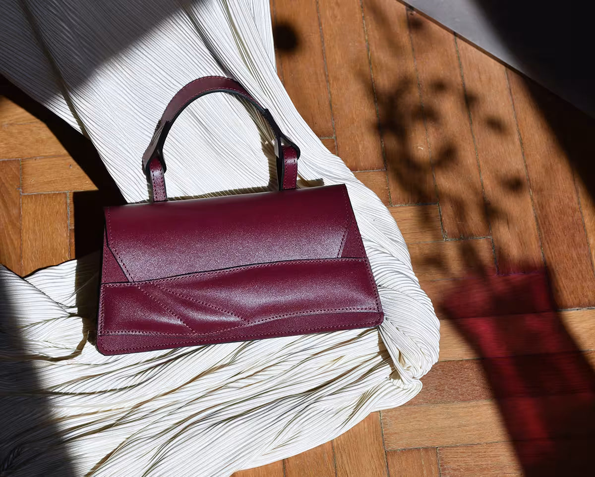 Handmade sculptural bag crafted from premium Italian nappa leather, black cherry red, oxblood coloured handbag, crossbody purse with unique wrist strap by Budapest based designer. Egyedi bordó bőr designer táska, kézzel festett élek, magyar tervezői márka.