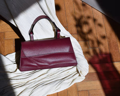 Handmade sculptural bag crafted from premium Italian nappa leather, black cherry red, oxblood coloured handbag, crossbody purse with unique wrist strap by Budapest based designer. Egyedi bordó bőr designer táska, kézzel festett élek, magyar tervezői márka.