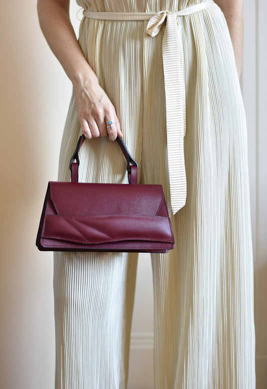 Handmade top handle bag crafted from genuine Italian leather, black cherry dark red handbag, crossbody purse with unique wrist strap by Hungarian, Budapest based designer. Egyedi cseresznye piros bőr designer táska,  magyar tervező márka.
