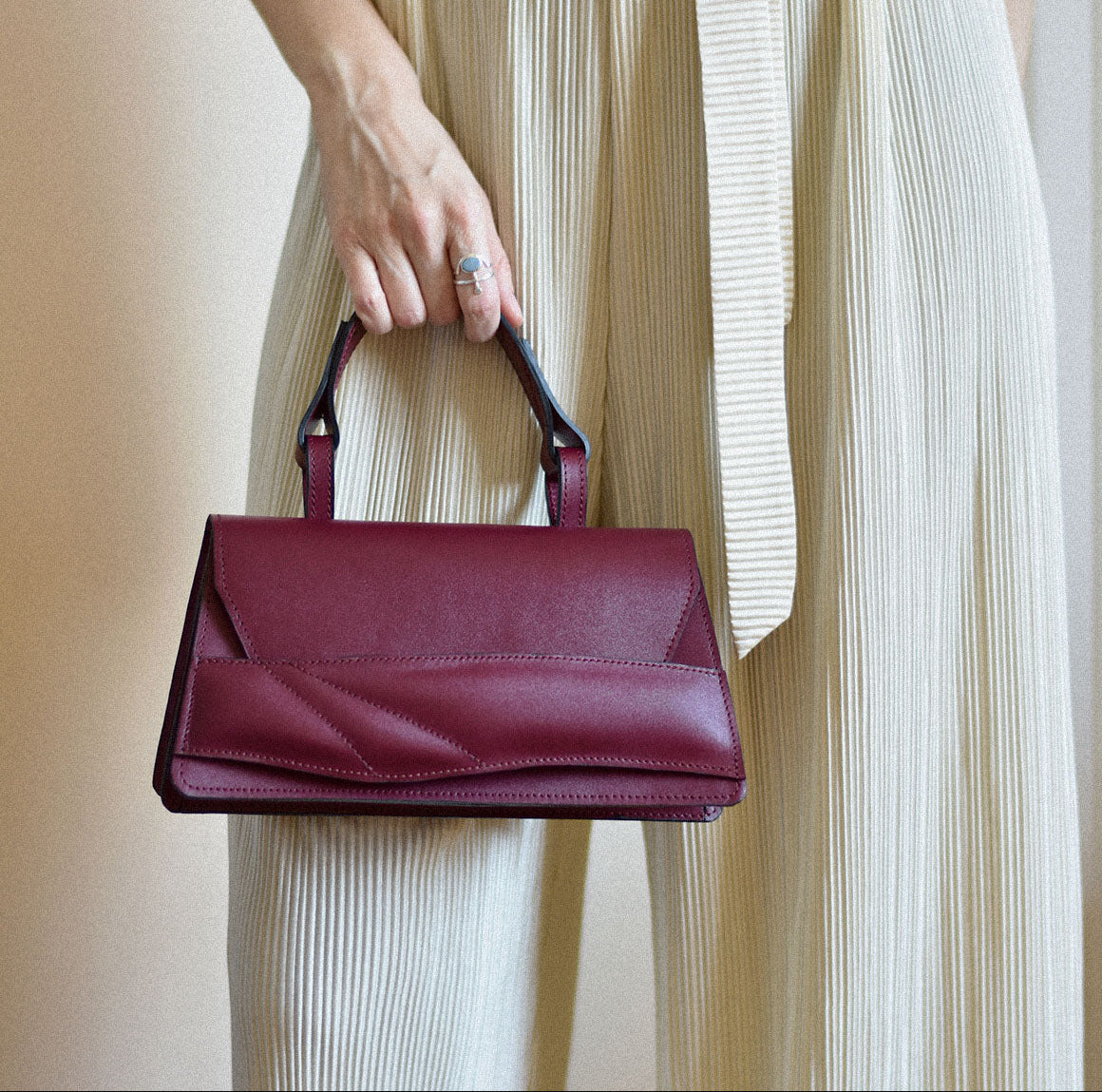 Handmade top handle bag crafted from genuine Italian leather, black cherry dark red handbag, crossbody purse with unique wrist strap by Hungarian, Budapest based designer. Egyedi cseresznye piros bőr designer táska,  magyar tervező márka.
