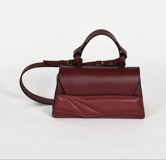 Magyar designer bőr crossbody táska, egyedi, női, uniszex, iparművész válltáska, különleges színekben, személyre szabott monogram, ajándék csomagolással. Handmade genuine leather dark red crossbody bag by Budapest based fashion designer, unique wrist strap handle, gift wrap available. Limited quantities, ethical production.