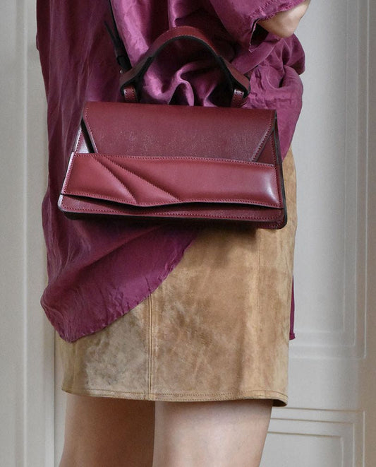 Magyar designer bőr crossbody táska, egyedi, női, uniszex, iparművész válltáska, különleges színekben, személyre szabott monogram, ajándék csomagolással. Handmade genuine leather dark red crossbody bag by Budapest based fashion designer, unique wrist strap handle, gift wrap available. Limited quantities, ethical production.