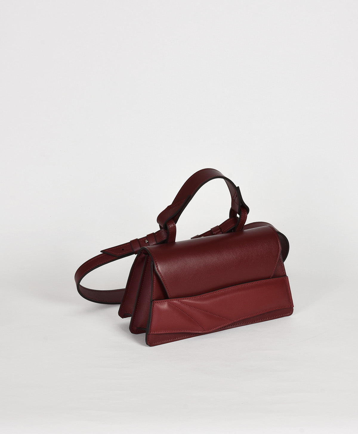 Burgundy red leather structured handbag with sculptural, matelasse wrist strap design and a top handle.. Bordó bőr lindasieto táska kézifogóval, vállpánttal, magyar tervezőtől.