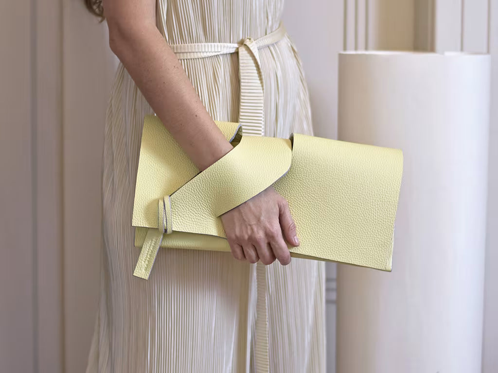 Lindasieto lemon cream, butter yellow leather Diagonal Slashed clutch purse, sculptural wrist strap design by Budapest based designer. Kortárs magyar designer vaj sárga bőr clutch táska,  különleges alkalmi outfit kézműves kiegészítő, művész tervező.