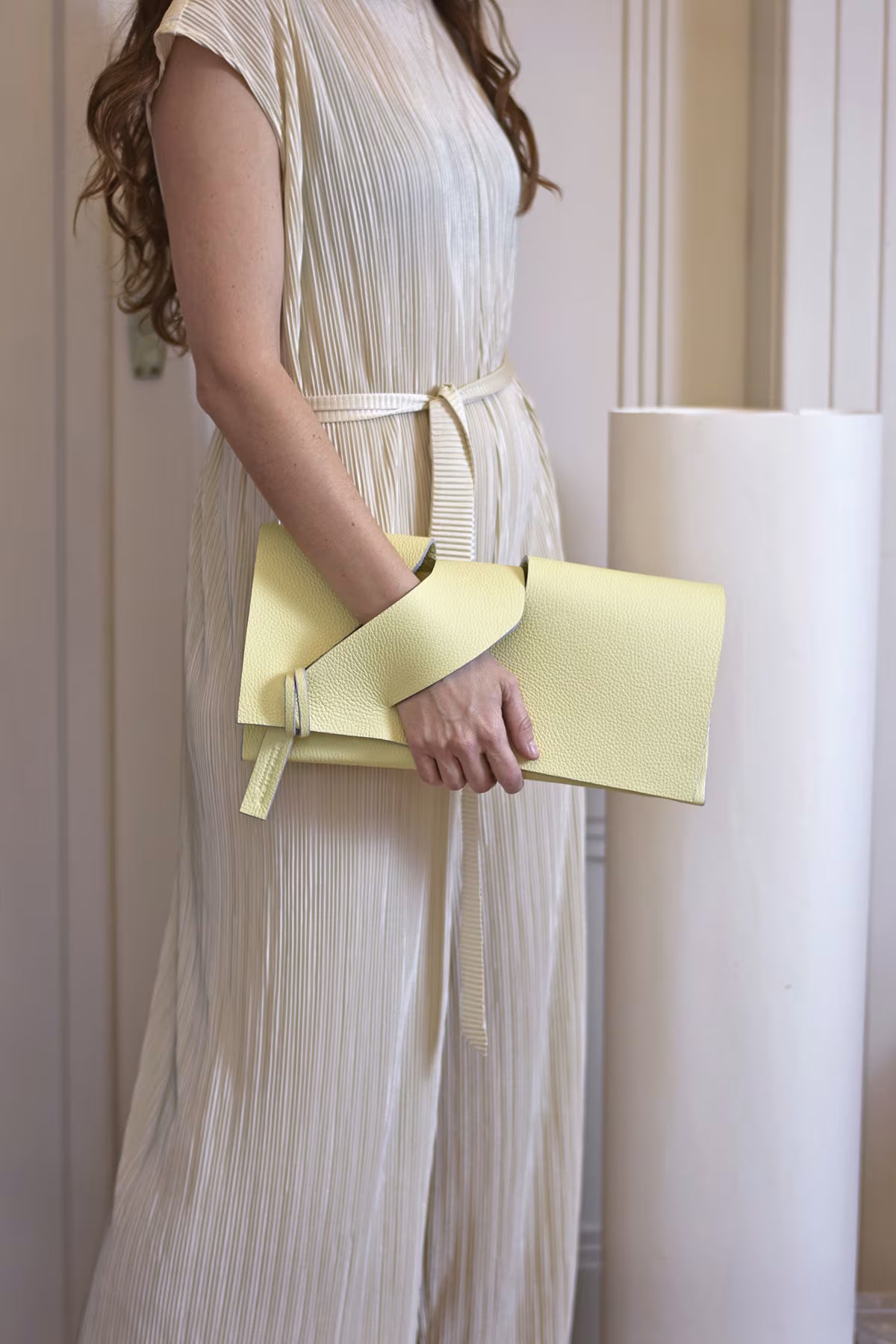 Lemon cream, butter yellow leather clutch purse, sculptural wrist strap design by Budapest based designer. Kortárs magyar designer vaj sárga bőr clutch táska,  különleges alkalmi outfit kézműves kiegészítő, művész tervező.