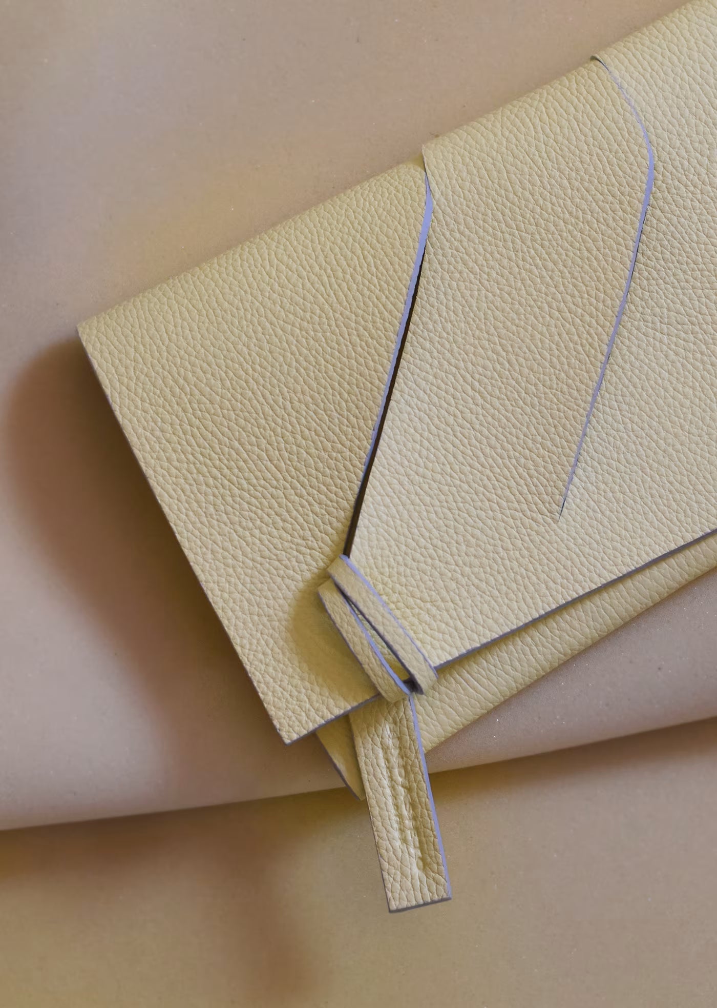 Lindasieto lemon cream, butter yellow leather Diagonal Slashed evening clutch purse, closeup on sculptural wrist strap design by Budapest based designer. Kortárs magyar designer vaj sárga bőr clutch táska,  különleges alkalmi outfit kézműves kiegészítő, művész tervező.