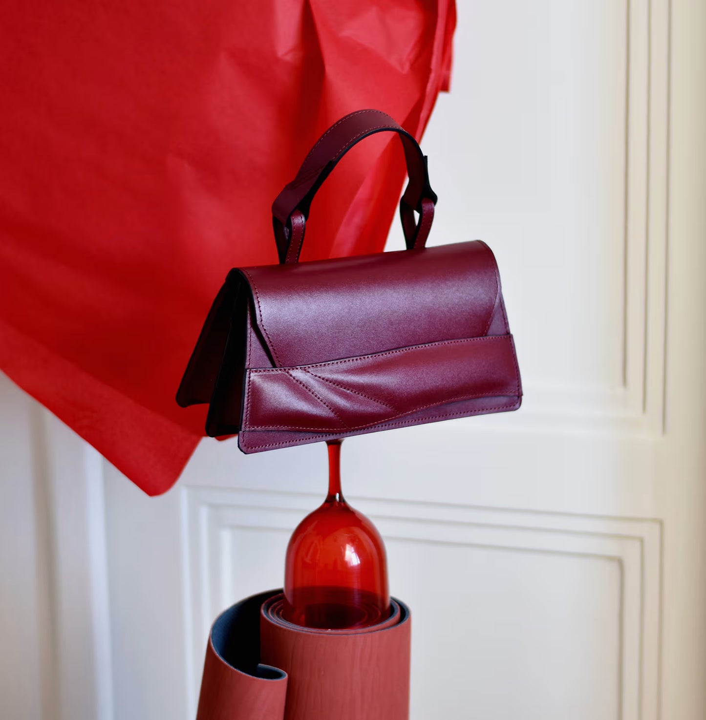 Lindasieto, sculptural, structured Mini Balance Bag crafted from premium Italian nappa leather, black cherry red, oxblood coloured handbag, crossbody purse with unique wrist strap by Budapest based designer Linda Sieto. Egyedi bordó bőr designer táska, kézzel festett élek, magyar tervezői márka.