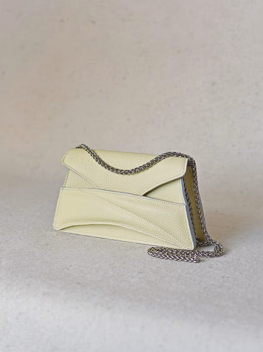 Butter pastel yellow textured, genuine leather designer clutch to crossbody bag, purse  with unique wrist strap, silver chain strap by Budapest based fashion brand. Egyedi, magyar valódi bőr táska, pasztell, vaj sárga női táska, ezüst lánc vállpánttal.