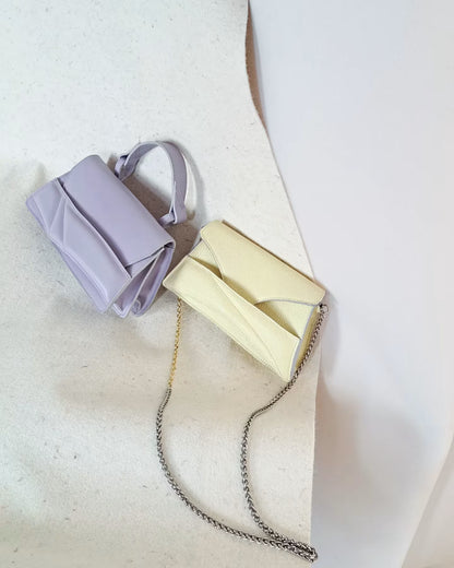 Butter pastel yellow textured, genuine leather designer clutch to crossbody bag, purse  with unique wrist strap, silver chain strap by Budapest based fashion brand. Egyedi, magyar valódi bőr táska, pasztell, vaj sárga női táska, ezüst lánc vállpánttal.