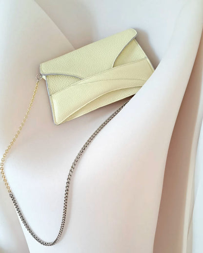 Butter pastel yellow textured, genuine leather designer clutch to crossbody bag, purse  with unique wrist strap, silver chain strap by Budapest based fashion brand. Egyedi, magyar valódi bőr táska, pasztell, vaj sárga női táska, ezüst lánc vállpánttal.