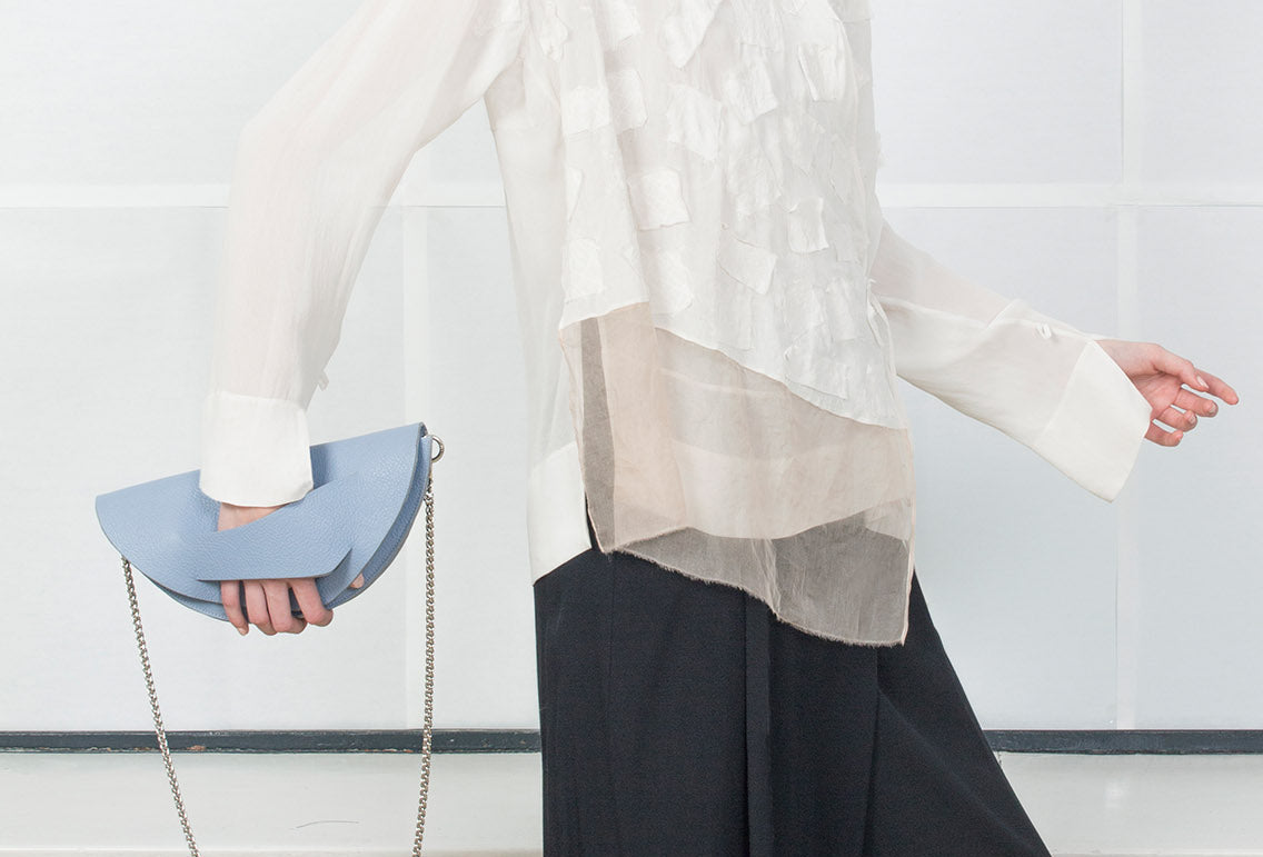 Lindasieto Dune Chain Bag handcrafted from luxurious Italian grained cornflower blue leather, sculptural minimalist handbag, crossbody purse with unique wrist strap by Hungarian, Budapest based designer. Pasztell kék bőr kortárs designer válltáska magyar táska tervező márka.