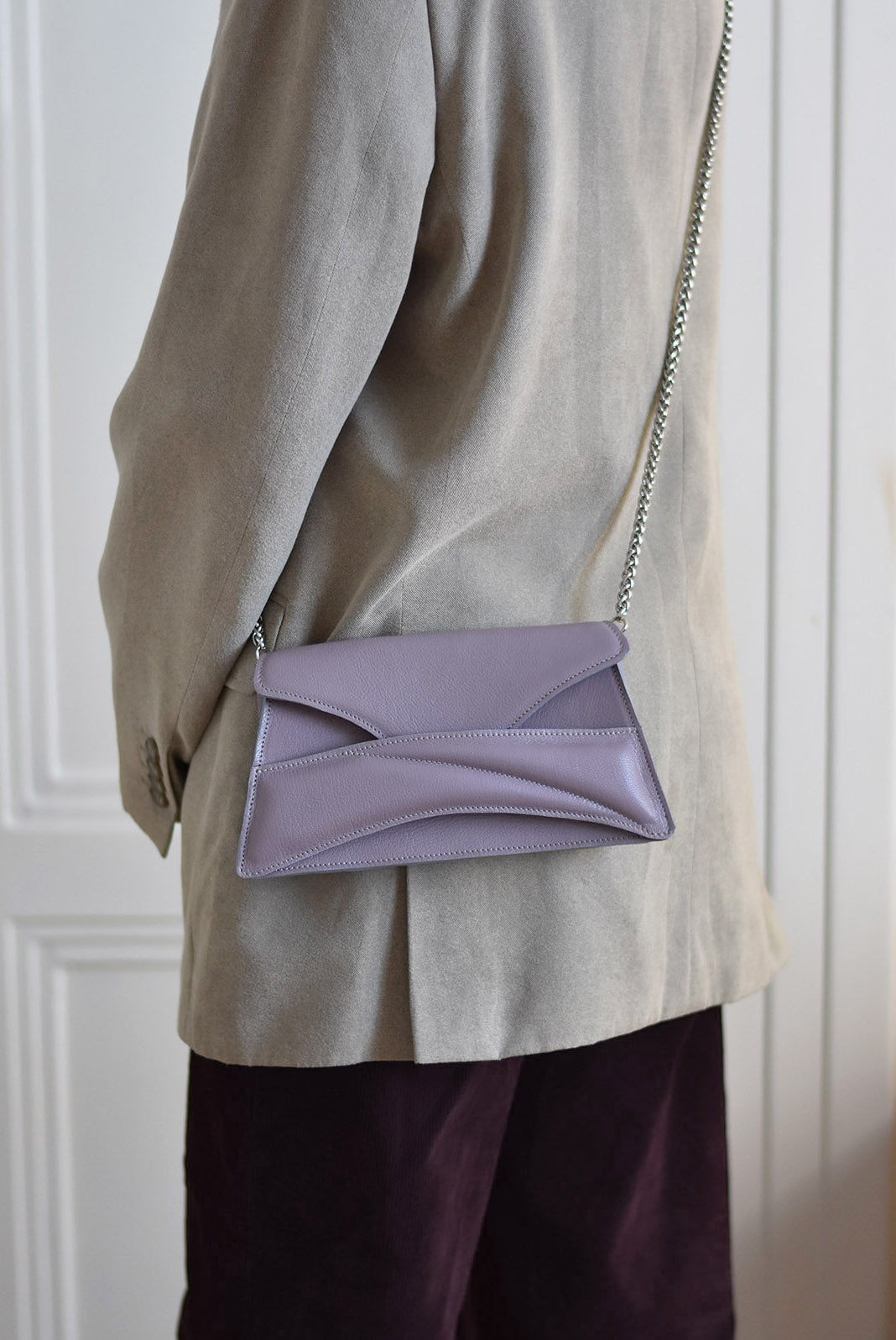 Lilac mauve leather designer clutch to crossbody bag, purse  with unique wrist strap, silver chain strap by Budapest based fashion brand, ss26. Egyedi magyar bőr borítéktáska, lila női táska, ezüst lánc vállpánttal 2026 tavasz színek.