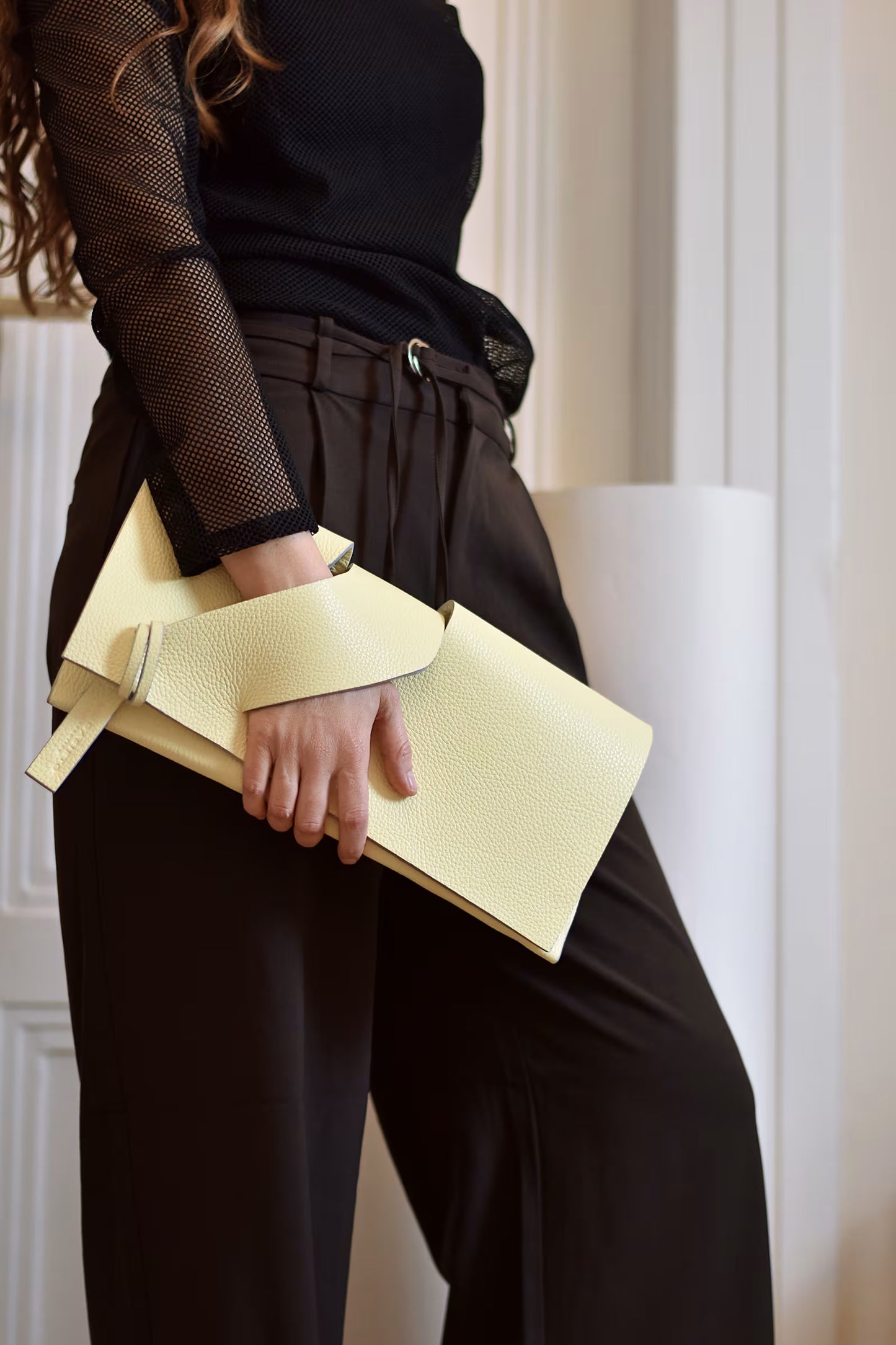 Lindasieto lemon cream, butter yellow leather Diagonal Slashed evening clutch purse, worn in hand with sculptural wrist strap, by Budapest based designer. Kortárs magyar designer vaj sárga bőr clutch táska,  különleges alkalmi outfit kézműves kiegészítő, művész tervező.