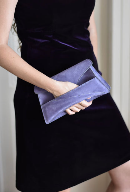 Lindasieto sculptural amethyst lilac suede leather Link Bag, designer occasion bag worn in hand with dark violet coloured elegant velvet outfit. Magyar kortárs designer lila velúr bőr alkalmi clutch táska, kézben viselve, elegáns padlizsán ruhával