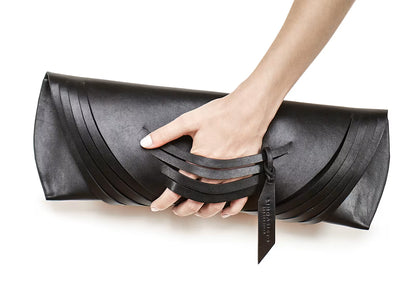 Lindasieto Curved Slashed Clutch bag crafted from black Italian leather, custom colors, sculptural, minimalist east west style purse with unique wrist strap by Budapest based independent designer. Fekete, választható színű bőr designer borítéktáska, táska, magyar táskatervező, magyar táska designer márka.