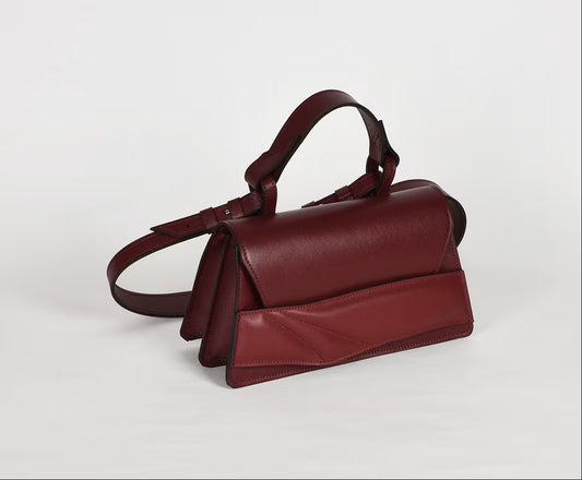 Magyar designer bőr crossbody táska, egyedi, női, uniszex, iparművész válltáska, különleges színekben, személyre szabott monogram, ajándék csomagolással. Handmade genuine leather dark red crossbody bag by Budapest based fashion designer, unique wrist strap handle, gift wrap available. Limited quantities, ethical production.