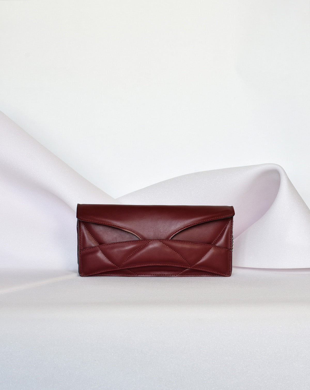 Lindasieto Abstract Heart Bag handcrafted from luxurious Italian dark red nappa leather, sculptural minimalist handbag, crossbody purse with unique wrist strap by Hungarian, Budapest based designer. Piros bordó bőr kortárs designer válltáska magyar táska tervező márka.