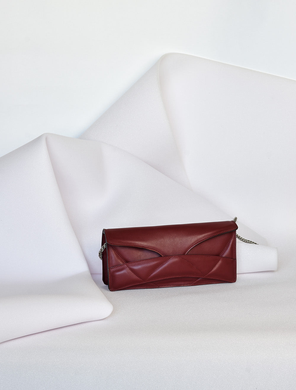 Lindasieto Abstract Heart Bag handcrafted from luxurious Italian dark red nappa leather, sculptural minimalist handbag, crossbody purse with unique wrist strap by Hungarian, Budapest based designer. Piros bordó bőr kortárs designer válltáska magyar táska tervező márka.