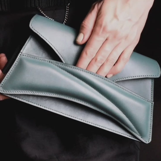 Lindasieto Link Bag, sculptural jade green leather clutch with a chain strap, close up detail of wrist strap and soft, green nappa leather texture. Magyar kortárs designer jade zöld bőr alkalmi női clutch táska, puha bőr csuklóőánt design és varrás részlete