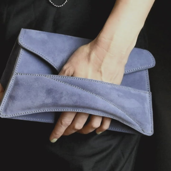 Lindasieto sculptural amethyst lilac suede leather Link Bag, designer crossbody handbag worn on the shoulder with black elegant minimal outfit. Magyar kortárs designer lila velúr bőr alkalmi clutch táska, kézben viselve, elegáns fekete neutrális öltözékkel