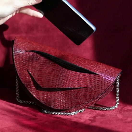 Video showing what fits inside a Lindasieto sculptural Mini Dune Bag, convertible clutch on chain with wrist strap in dark red, burgundy Italian leather. Limited numbers, custom colors, personalization, Budapest based designer. Lindasieto Mini Dune egyedi bordó bőr designer táska, magyar iparművész táska tervező,  prémium olasz bőrök, személyre szabott ajándék, monogram, magyar márka.