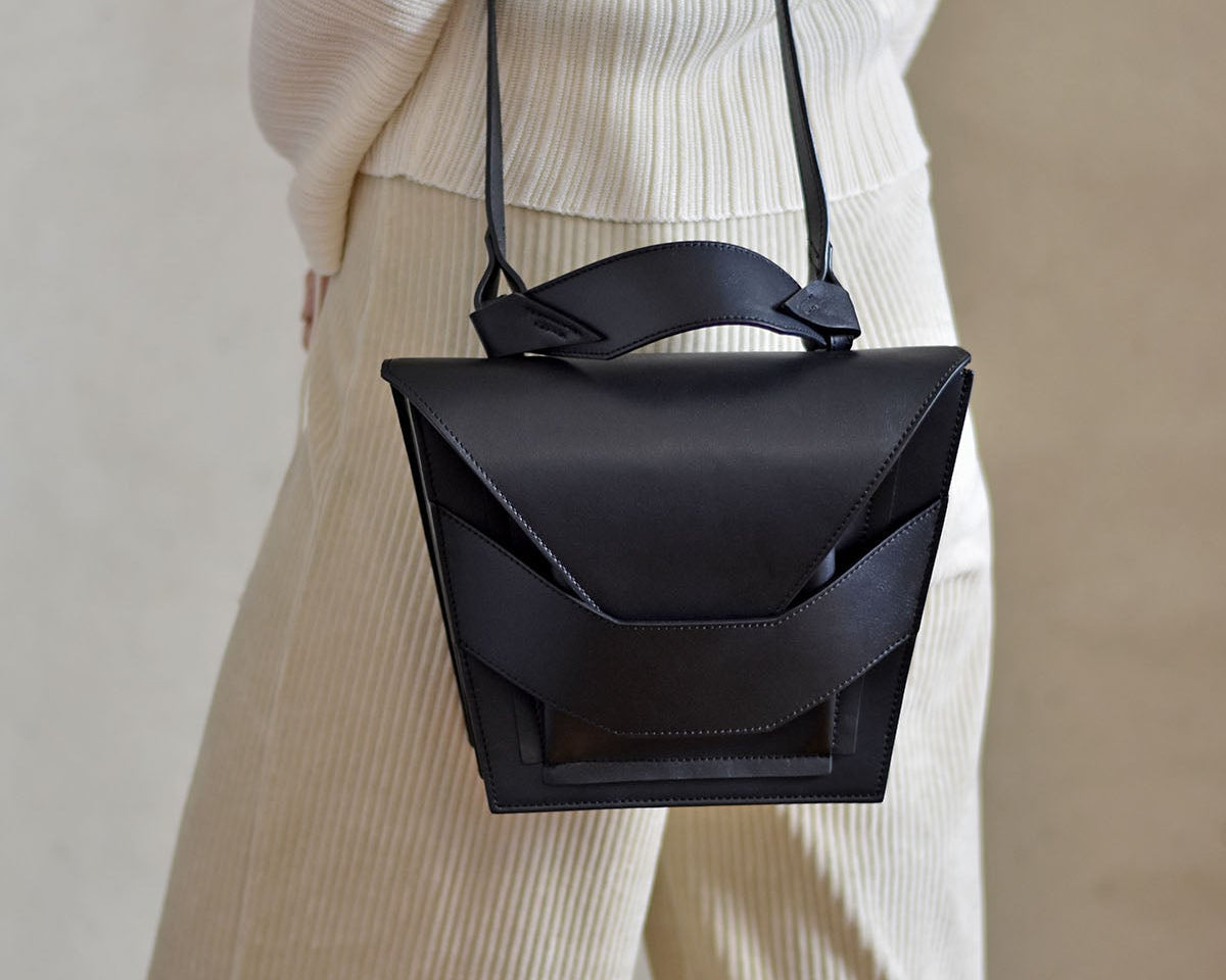 Avantgarde edgy bag handcrafted from genuine Italian leather, custom colors, black handbag, crossbody purse with unique wrist strap by Hungarian, Budapest based designer. Fekete, választható színű bőr designer válltáska magyar táska tervező márka.