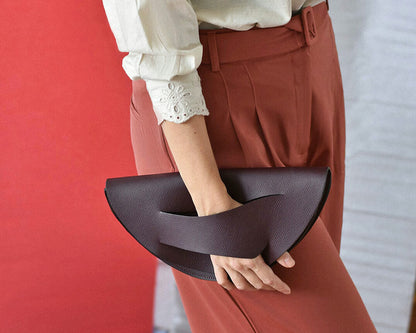 Modern clutch bag handcrafted from genuine Italian leather, dark red burgundy garnet wine red handbag, crossbody purse with unique wrist strap by Hungarian, Budapest based designer. Bordó választható színű bőr designer borítéktáska, táska, válltáska magyar tervezői márka.