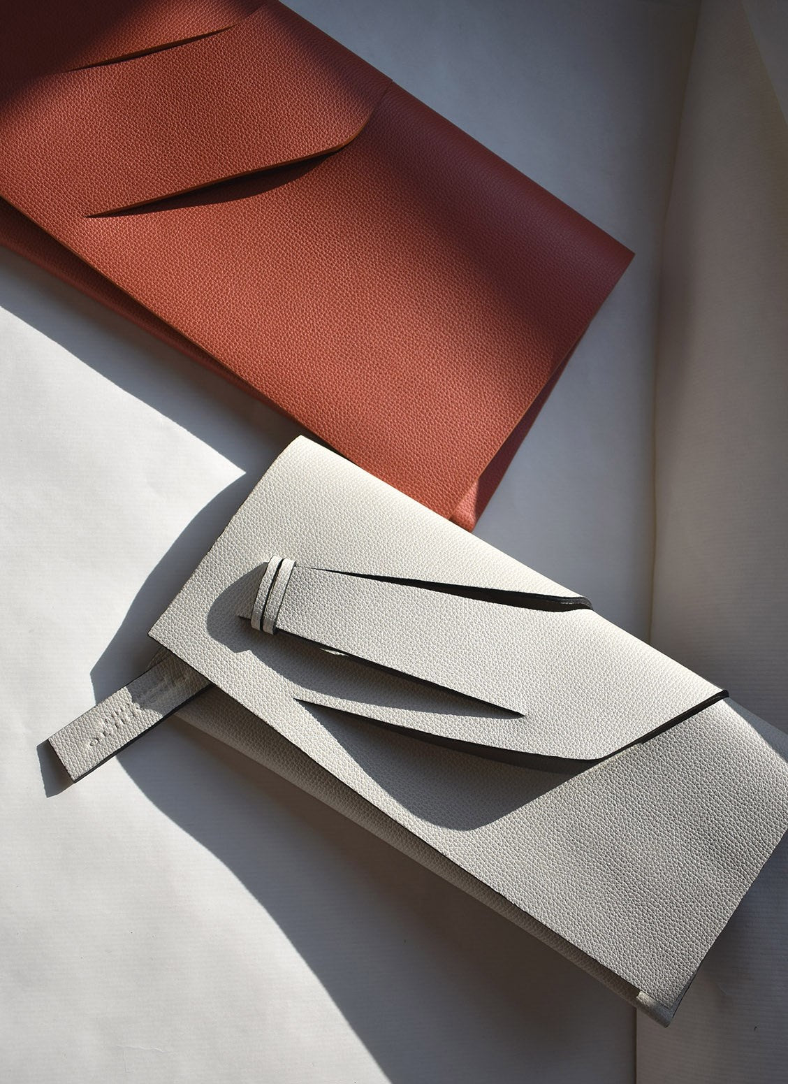 Handmade clutch bag handcrafted from genuine Italian leather, custom colors, orange, off white handbag, purse with unique wrist strap by Hungarian, Budapest based designer. Fehér, narancs választható színű bőr designer borítéktáska, táska, magyar táskatervező márka.