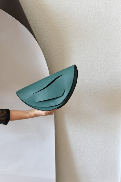 Sculptural clutch bag handcrafted from Italian jade green nappa leather, crossbody purse with unique wrist strap by Hungarian, Budapest based designer. Zöld bőr designer borítéktáska, táska, válltáska magyar táskatervező márka.
