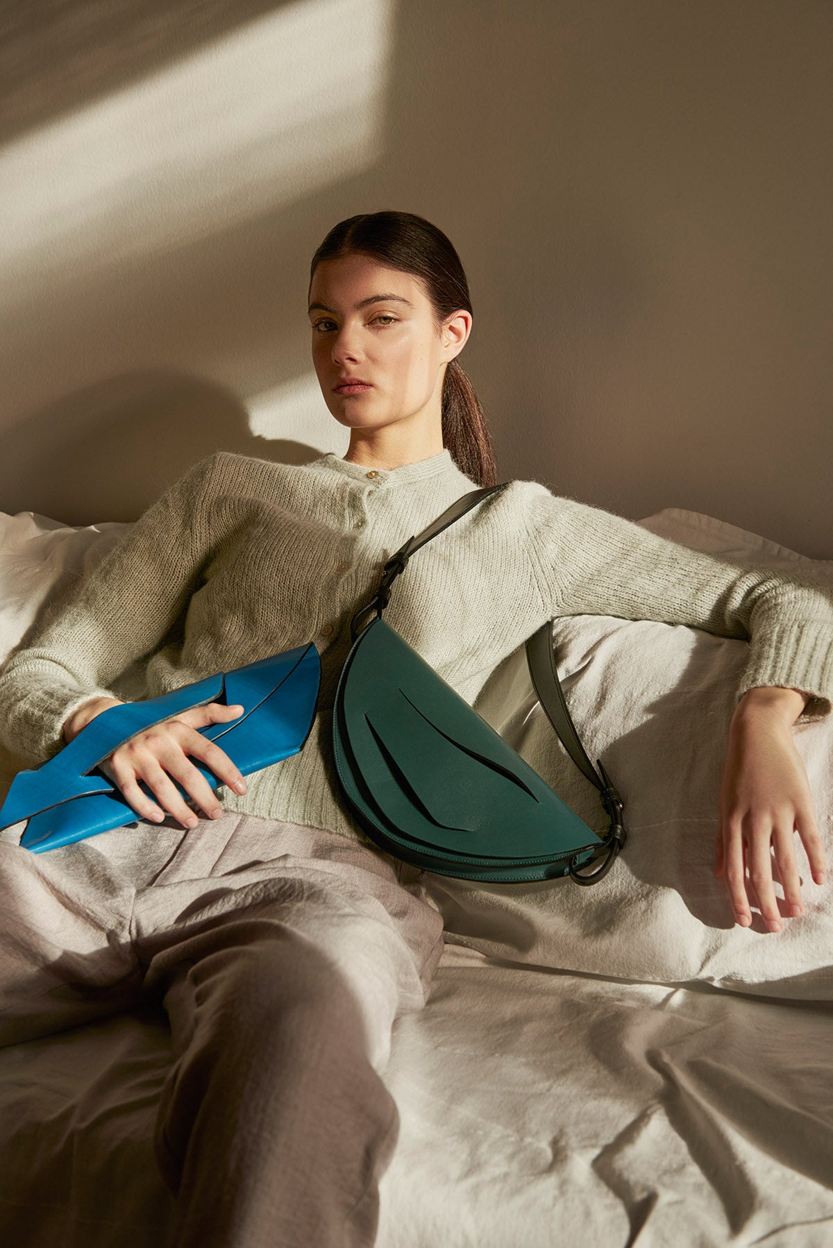 Sculptural clutch bag handcrafted from Italian jade green nappa leather, crossbody purse with unique wrist strap by Hungarian, Budapest based designer. Zöld bőr designer borítéktáska, táska, válltáska magyar táskatervező márka.