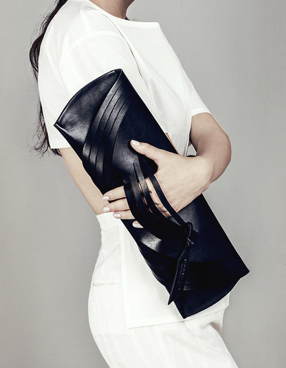 Lindasieto Curved Slashed Clutch bag crafted from black Italian leather, custom colors, sculptural, minimalist east west style purse with unique wrist strap by Budapest  independent designer. Fekete, választható színű bőr designer borítéktáska, táska, magyar táskatervező, magyar táska designer márka.